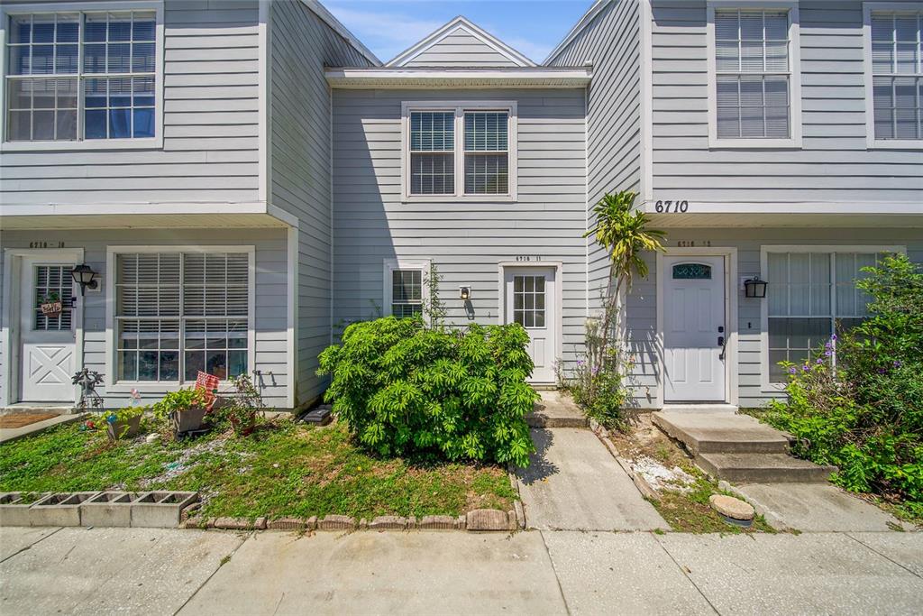 A three-unit townhouse exterior with light gray siding, multiple windows, and small front entryways — 6710 121ST AVENUE UNIT 11, LARGO, FL