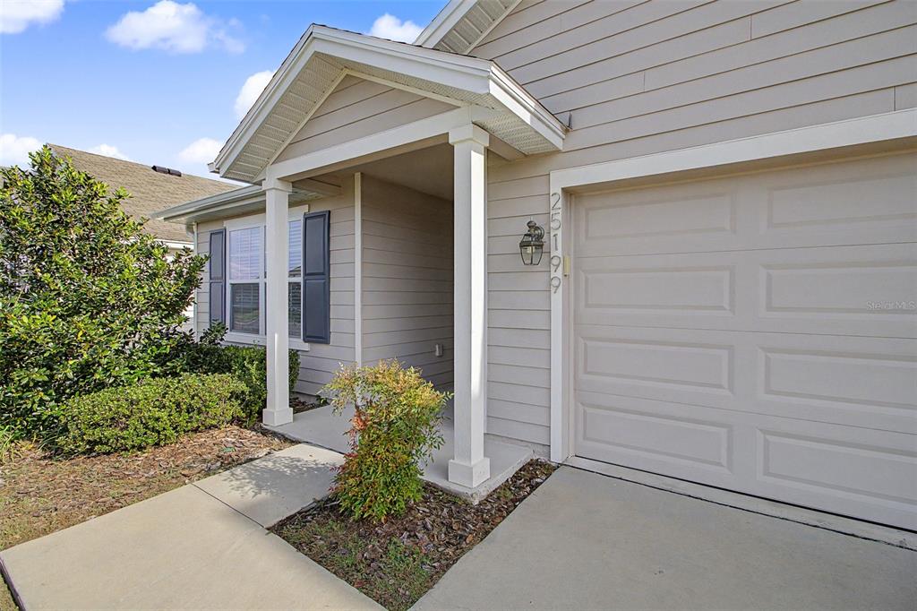 The exterior of a house features beige siding, a garage door, and a covered entryway — 25199 NW 8TH ROAD, NEWBERRY, FL