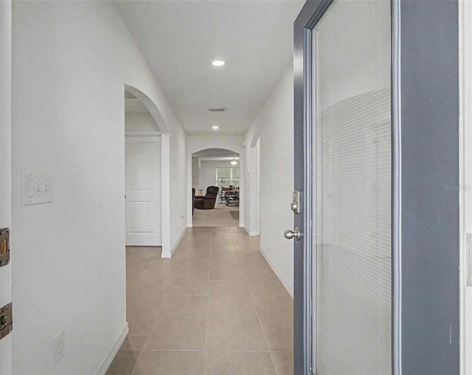A view from an open front door into a tiled hallway with arched doorways — 25199 NW 8TH ROAD, NEWBERRY, FL