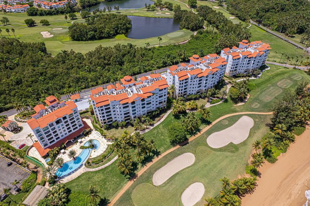 An aerial view shows a large apartment complex situated next to a golf course and ocean — Ocean Sixteen 9000 RIO MAR BLVD UNIT 321, RIO GRANDE, PR