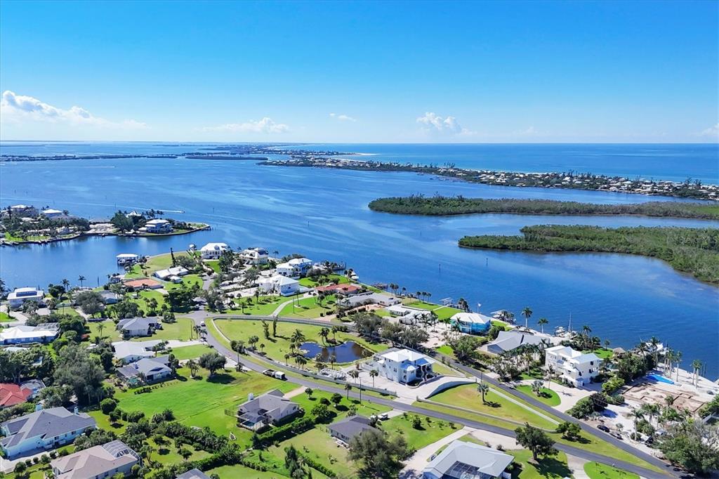 An aerial view shows waterfront homes, lush green lawns, and a small pond near the coast — 342 GREEN DOLPHIN DRIVE, PLACIDA, FL