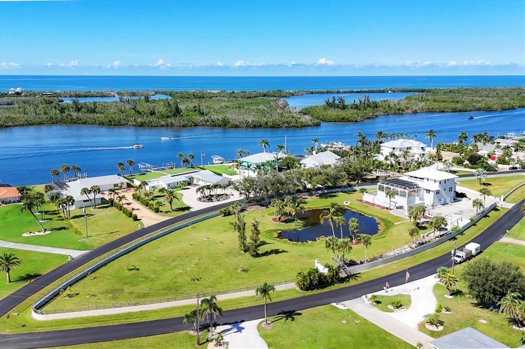 An aerial view shows waterfront homes, a central pond, and a road near the ocean — 342 GREEN DOLPHIN DRIVE, PLACIDA, FL