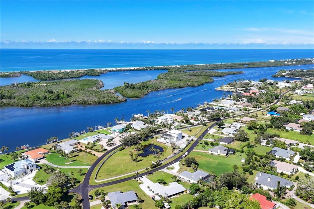 An aerial view shows a coastal neighborhood with houses, a central pond, and a waterway — 342 GREEN DOLPHIN DRIVE, PLACIDA, FL