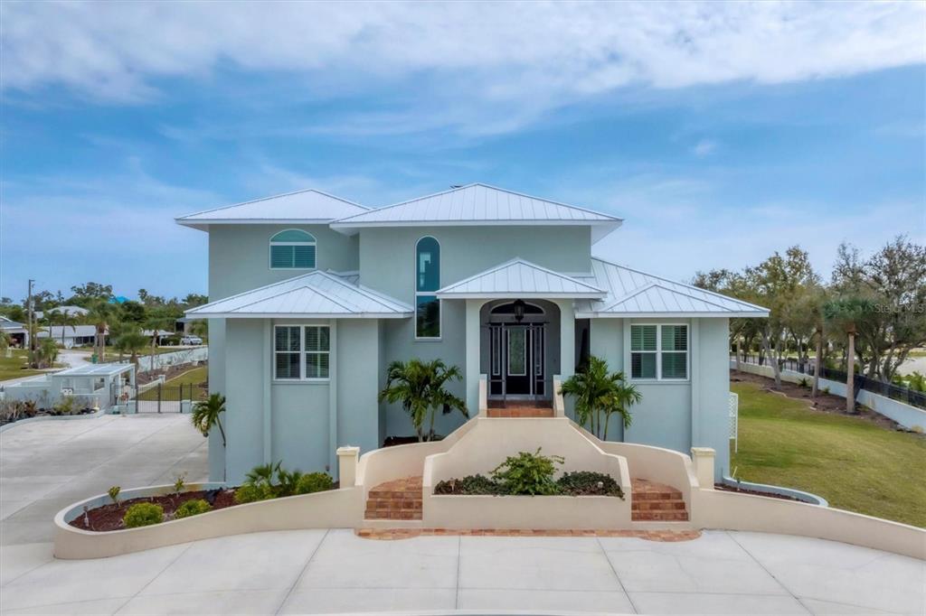A two-story light green house with a metal roof and a raised front entryway — 342 GREEN DOLPHIN DRIVE, PLACIDA, FL