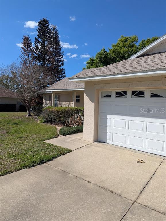 A view of a house exterior featuring a white garage door and a concrete driveway — 108 TWIN LAKE CIRCLE, UMATILLA, FL