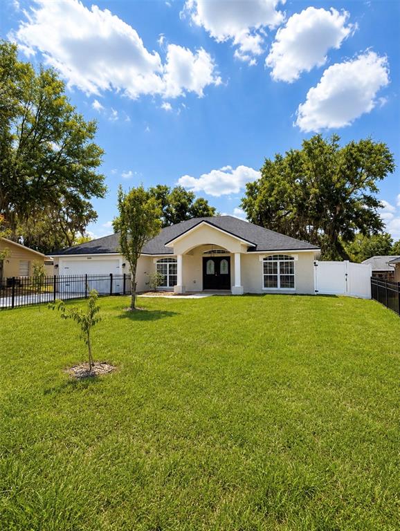 A single-story house with a white exterior, dark roof, and a front lawn — 10058 SE 105TH PLACE, BELLEVIEW, FL