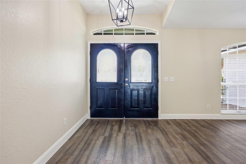An entryway features dark blue double doors, wood-look flooring, and a geometric pendant light — 10058 SE 105TH PLACE, BELLEVIEW, FL