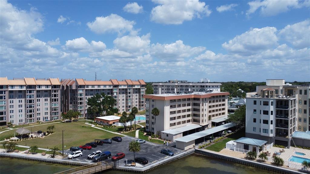 An aerial view shows multi-story apartment buildings with parking lots and a waterfront bulkhead — 620 EDGEWATER DRIVE UNIT 102, DUNEDIN, FL