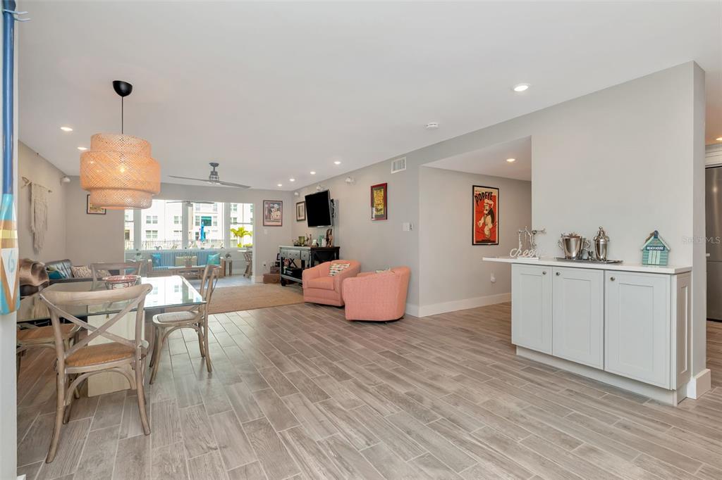An open-concept living and dining area features light wood-look tile flooring and a wet bar — 620 EDGEWATER DRIVE UNIT 102, DUNEDIN, FL