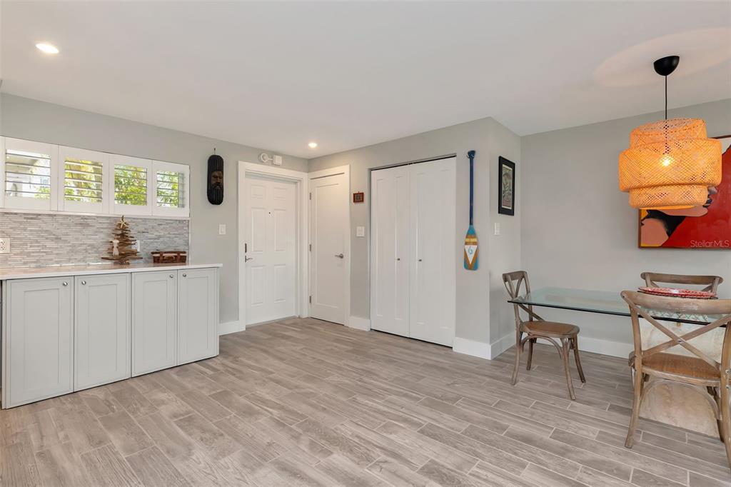 A dining area features light wood-look tile flooring, white cabinetry, and a woven pendant light — 620 EDGEWATER DRIVE UNIT 102, DUNEDIN, FL