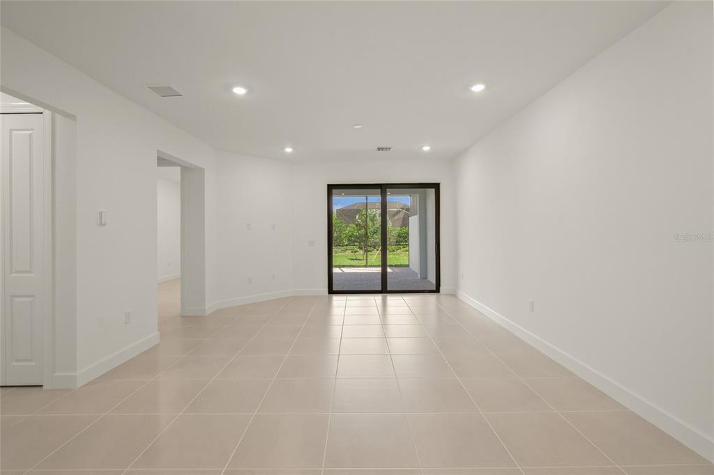 An empty room with white walls, tiled floors, recessed lighting, and sliding glass patio doors — 14860 MISTY POND LOOP, NOKOMIS, FL