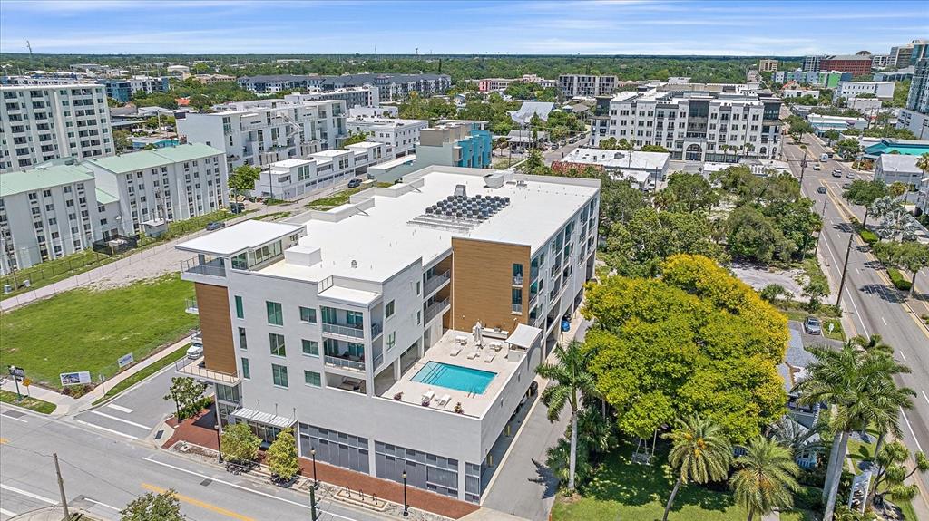 An aerial view of a modern apartment building featuring a rooftop pool and surrounding neighborhood — 332 COCOANUT AVENUE UNIT 406, SARASOTA, FL