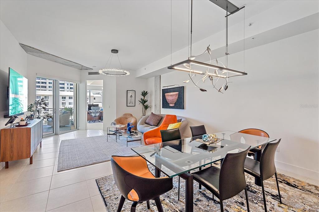 A modern open-concept living and dining area features tile floors, glass furniture, and contemporary lighting — 332 COCOANUT AVENUE UNIT 406, SARASOTA, FL