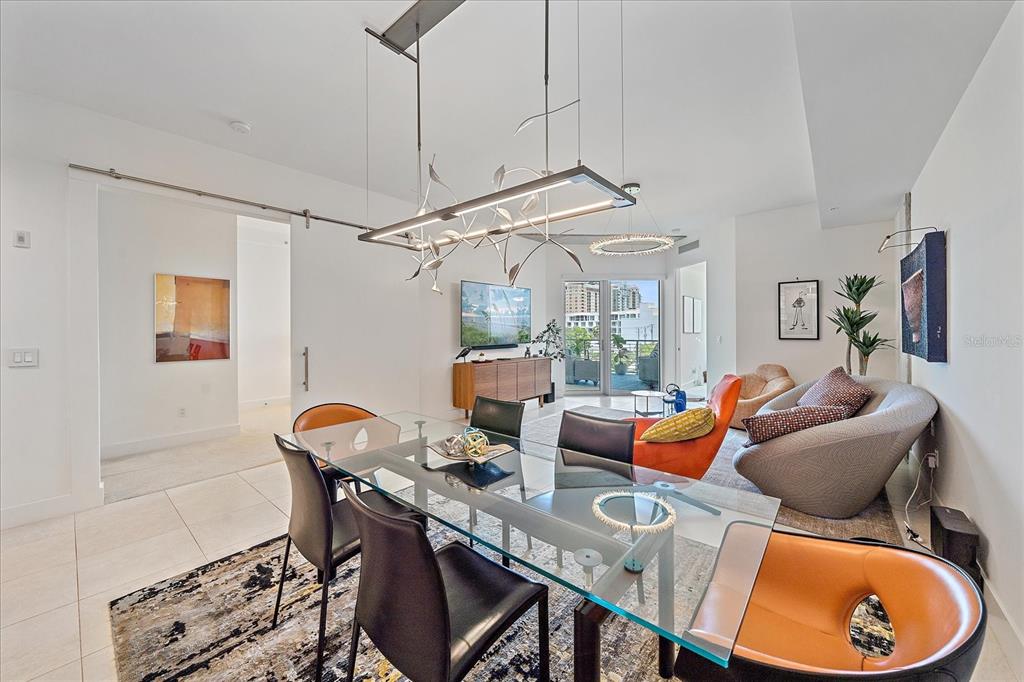 A modern dining area features a glass table, black chairs, and a unique light fixture — 332 COCOANUT AVENUE UNIT 406, SARASOTA, FL