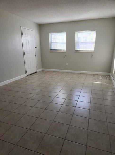 An empty room with light-colored walls, tiled flooring, a white door, and two windows — 817 SKY LAKE CIRCLE UNIT A, ORLANDO, FL