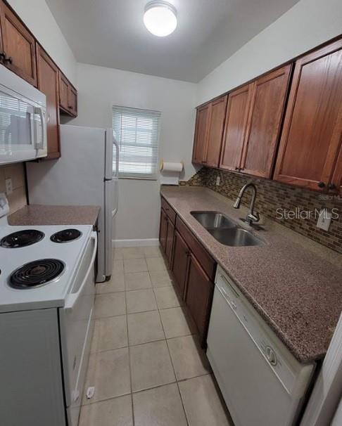 A kitchen with wood cabinets, granite countertops, white appliances, and a tiled backsplash — 817 SKY LAKE CIRCLE UNIT A, ORLANDO, FL