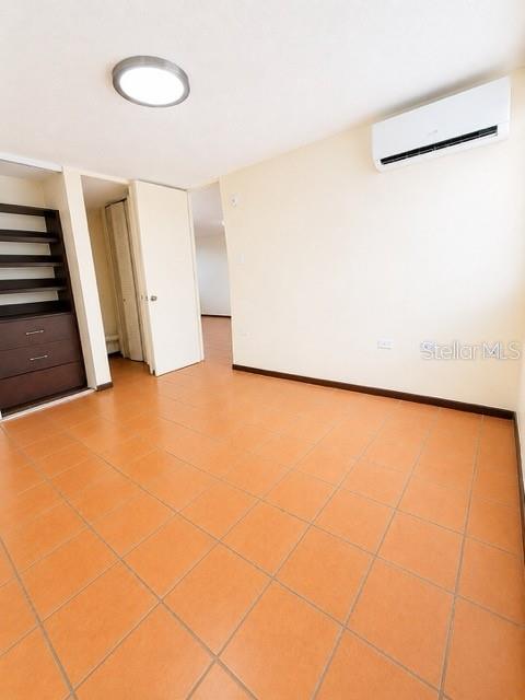 An empty room features orange tile flooring, a wall-mounted air conditioner, and built-in shelving — 1203 GOLDEN VILLAS, VEGA ALTA, PR