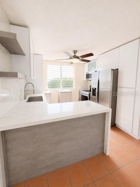 A modern kitchen features white cabinets, a gray island, stainless steel appliances, and tile flooring — 1203 GOLDEN VILLAS, VEGA ALTA, PR