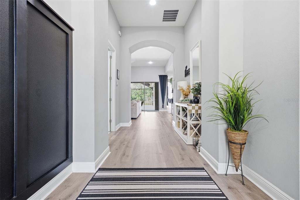 A hallway with light wood flooring, a striped rug, and a potted plant — 13819 MOONSTONE CANYON DRIVE, RIVERVIEW, FL