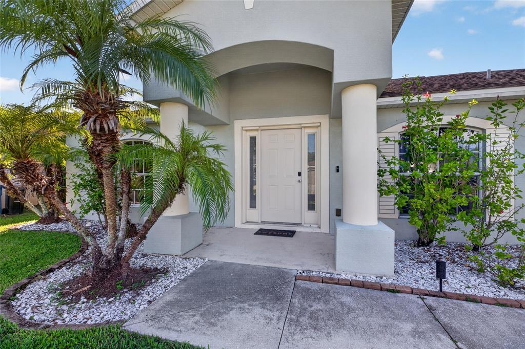 The front entrance of a house features a white door, two columns, and palm trees — 2502 NATURE POINTE LOOP, FORT MYERS, FL