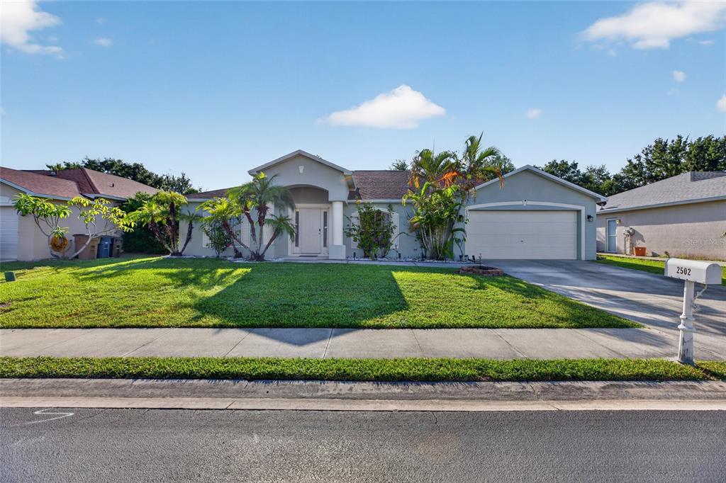 A single-story house with a beige stucco exterior, a two-car garage, and a front lawn — 2502 NATURE POINTE LOOP, FORT MYERS, FL