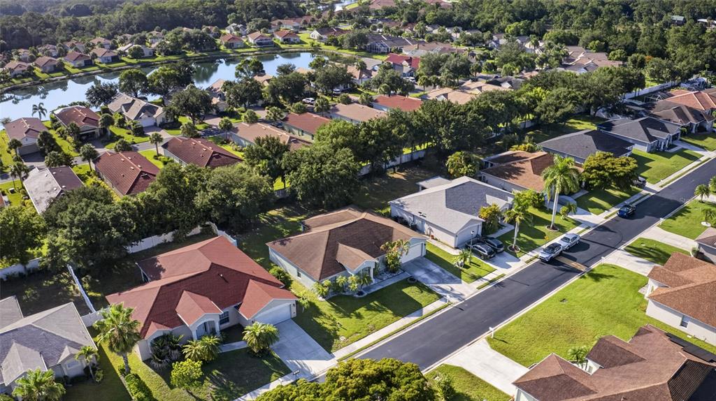 An aerial view shows a suburban neighborhood with single-family homes, paved streets, and a lake — 2502 NATURE POINTE LOOP, FORT MYERS, FL