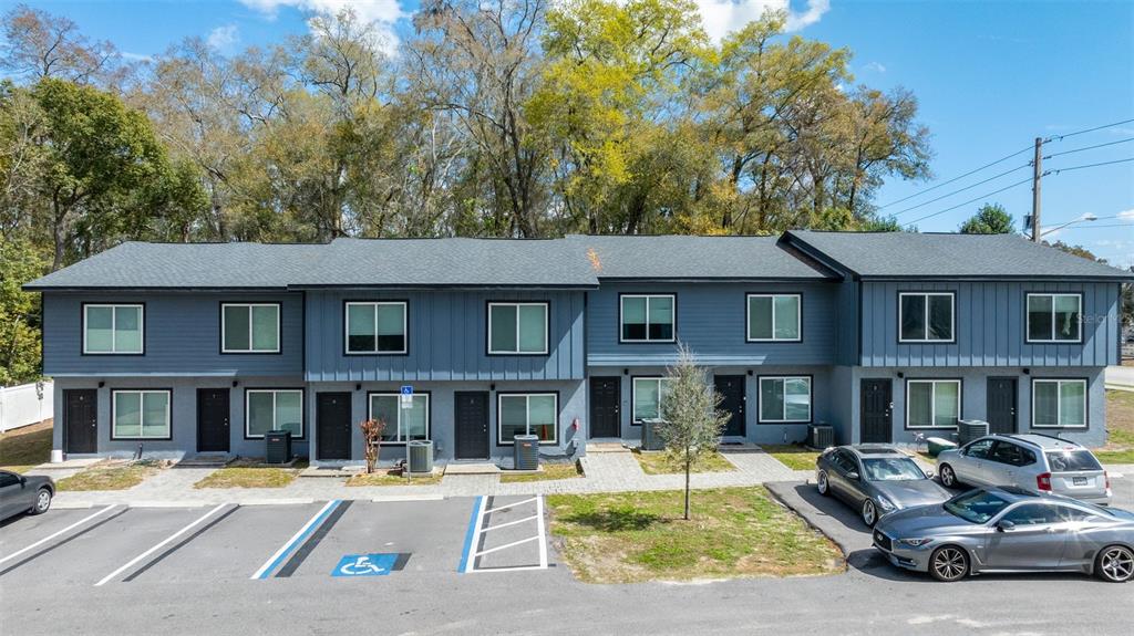 A two-story blue apartment building with a parking lot and trees in the background — 3041 SW 20TH STREET, OCALA, FL