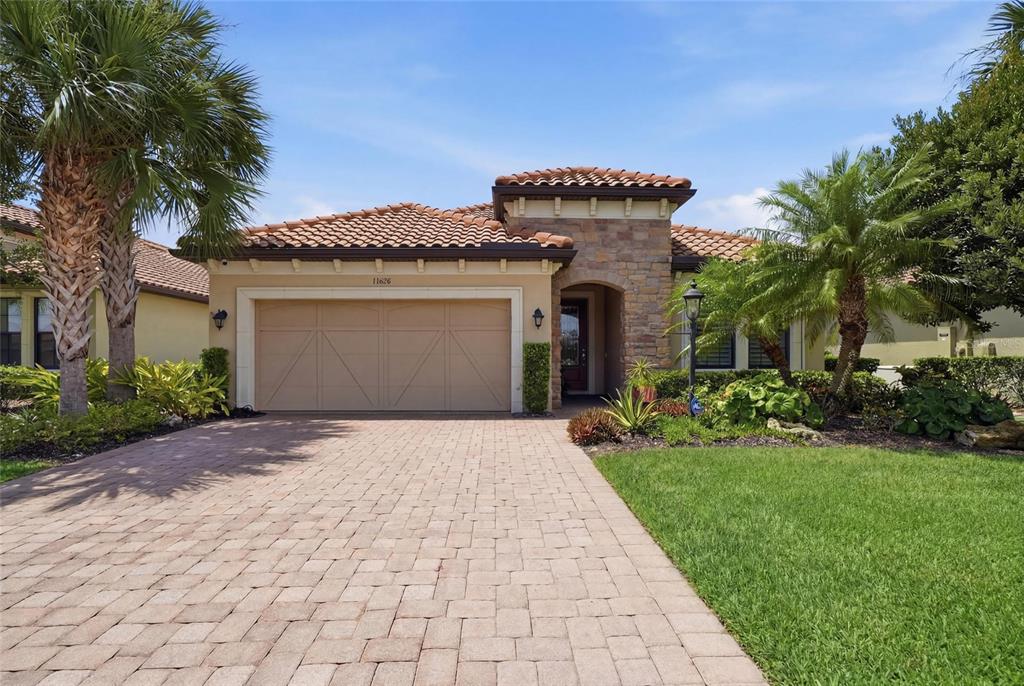 A single-story house with a tile roof, stone facade, and a two-car garage — 13038 PRIMA DRIVE, BRADENTON, FL