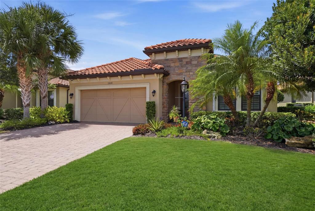 A stone-arched entryway leads to a brown front door with a glass insert — 13038 PRIMA DRIVE, BRADENTON, FL
