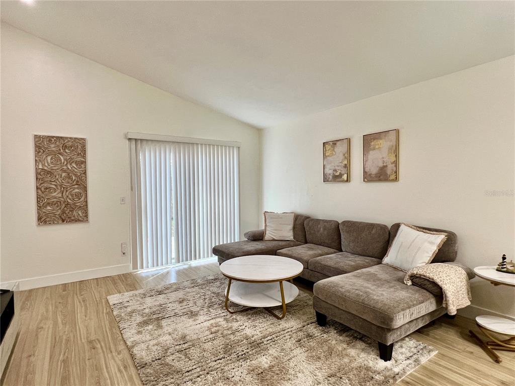 A living room features a sectional sofa, a round coffee table, and wall art — 962 STONYBROOK CIRCLE, PORT ORANGE, FL