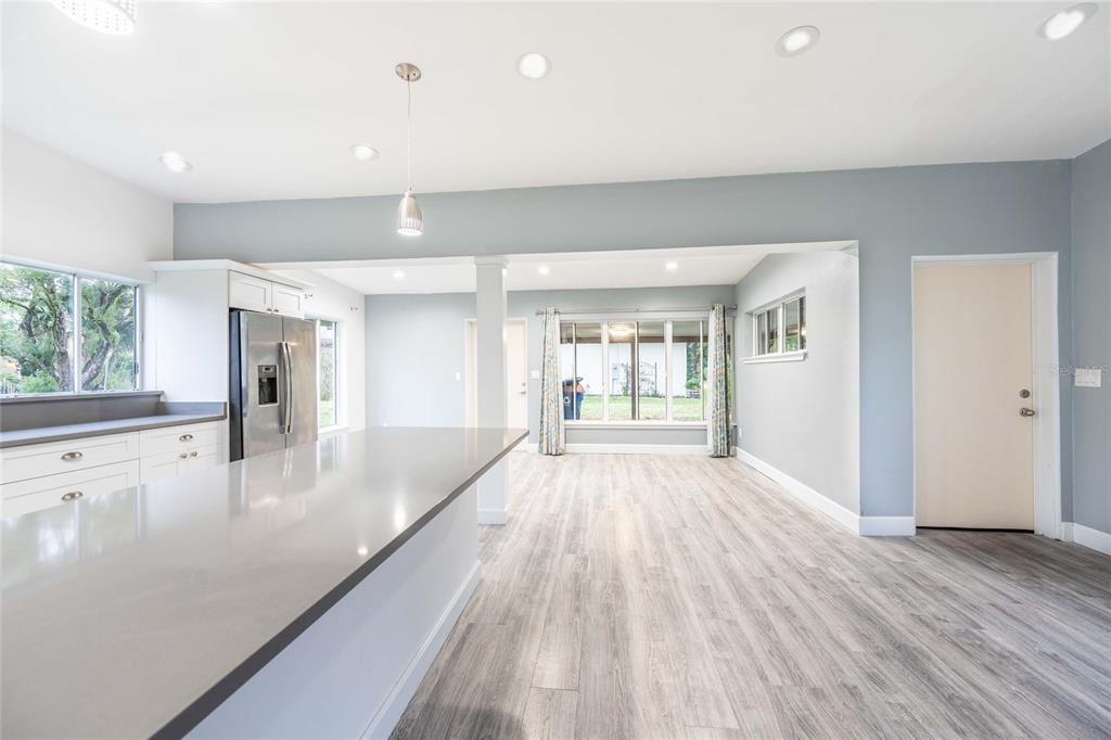A modern kitchen with a gray island, stainless steel refrigerator, and light wood-look flooring — 2231 NAIRN DRIVE, WINTER PARK, FL