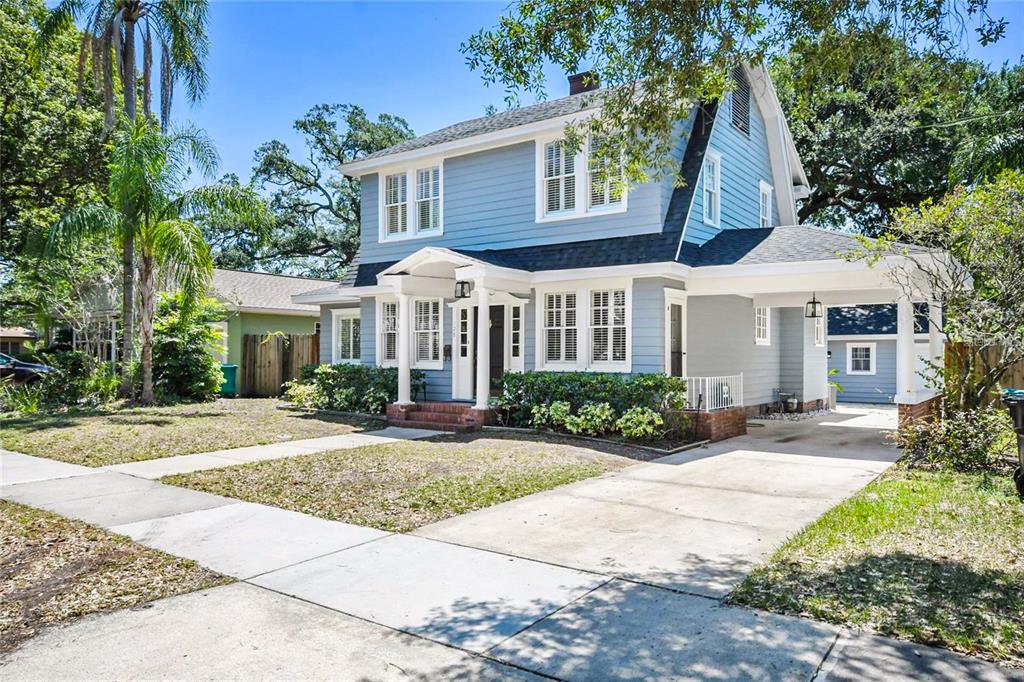 A two-story blue house with a front porch, white trim, and an attached carport — 128 WISTERIA AVENUE, ORLANDO, FL