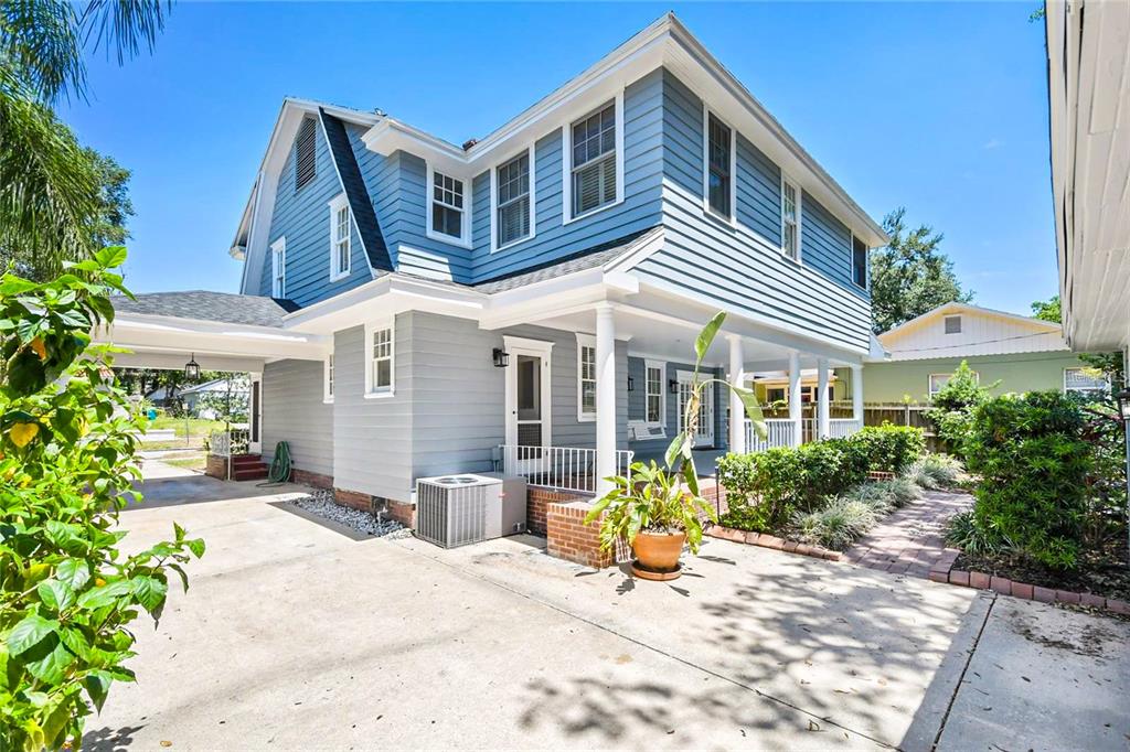 A two-story blue house with a covered porch, concrete driveway, and a small air conditioner — 128 WISTERIA AVENUE, ORLANDO, FL