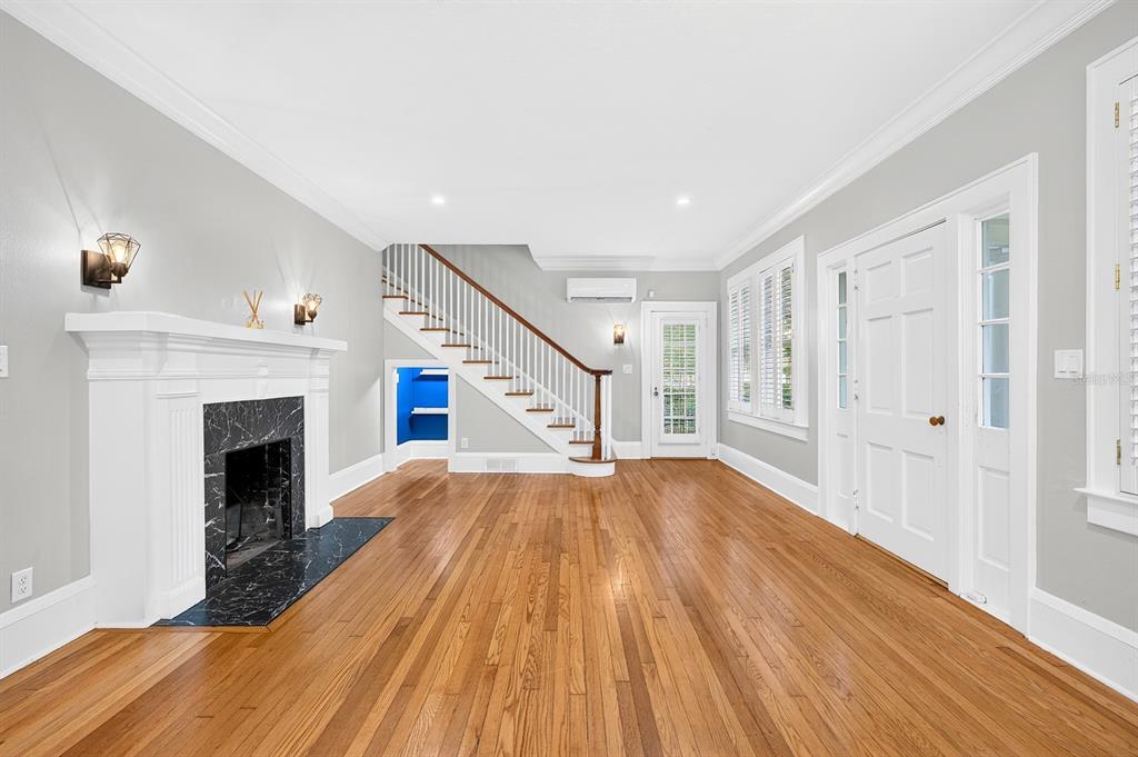 A living room with hardwood floors, a white sofa, two armchairs, and a fireplace — 128 WISTERIA AVENUE, ORLANDO, FL