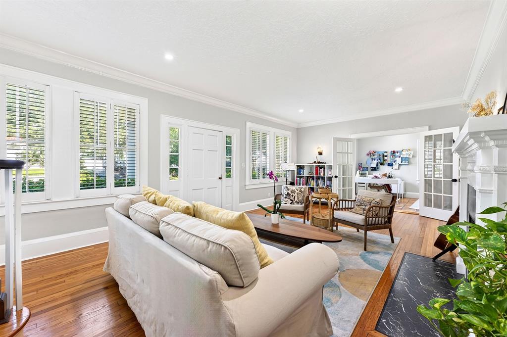 A living room with hardwood floors, a white sofa, two armchairs, and a fireplace — 128 WISTERIA AVENUE, ORLANDO, FL