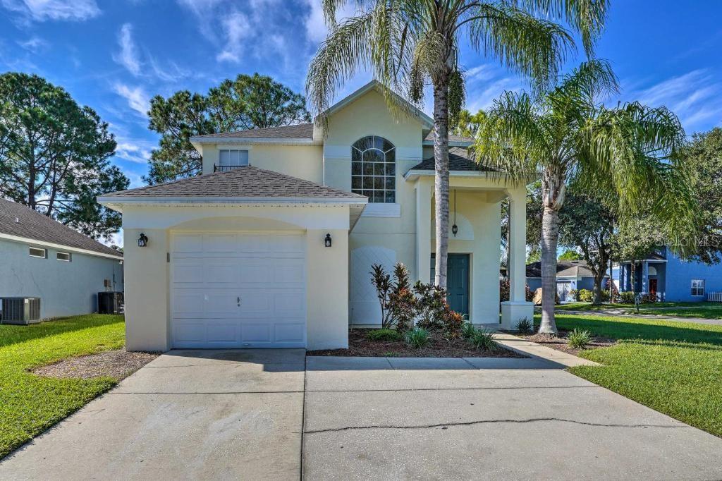 A two-story, light-yellow suburban house with a single-car garage and a palm tree out front — 2984 KOKOMO LOOP, HAINES CITY, FL