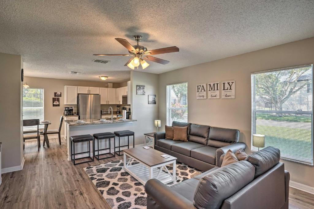 An open-concept living room and kitchen featuring grey sofas, a breakfast bar, and wood flooring — 2984 KOKOMO LOOP, HAINES CITY, FL