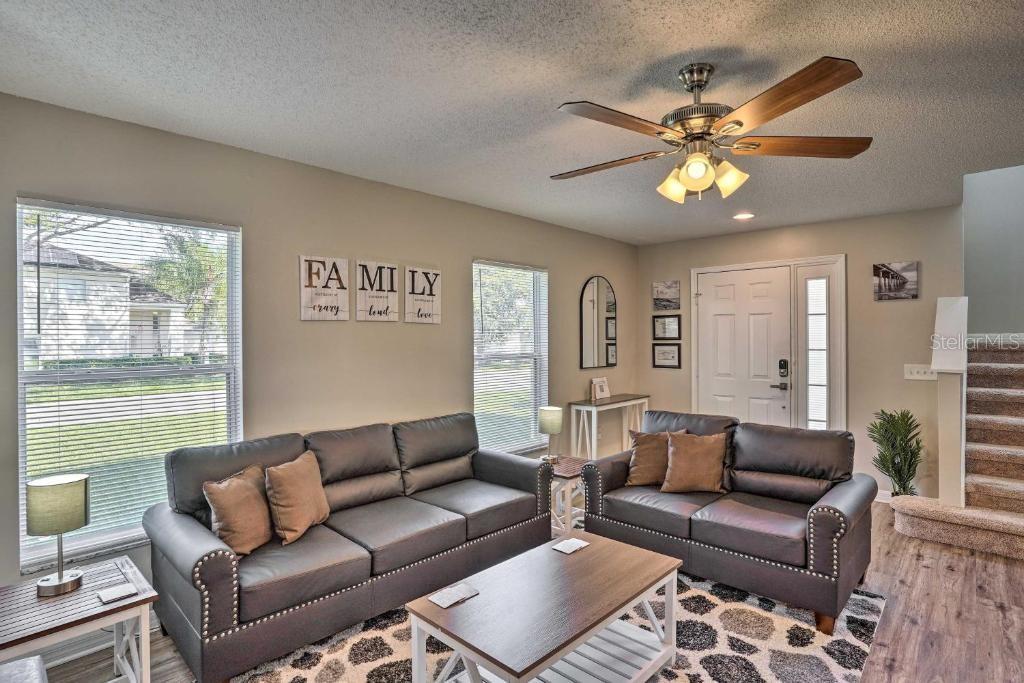 A living room features two dark gray sofas, a coffee table, and a ceiling fan — 2984 KOKOMO LOOP, HAINES CITY, FL