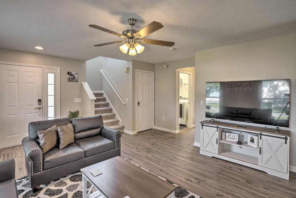 A living room features a gray sofa, wood-look flooring, a ceiling fan, and a television console — 2984 KOKOMO LOOP, HAINES CITY, FL