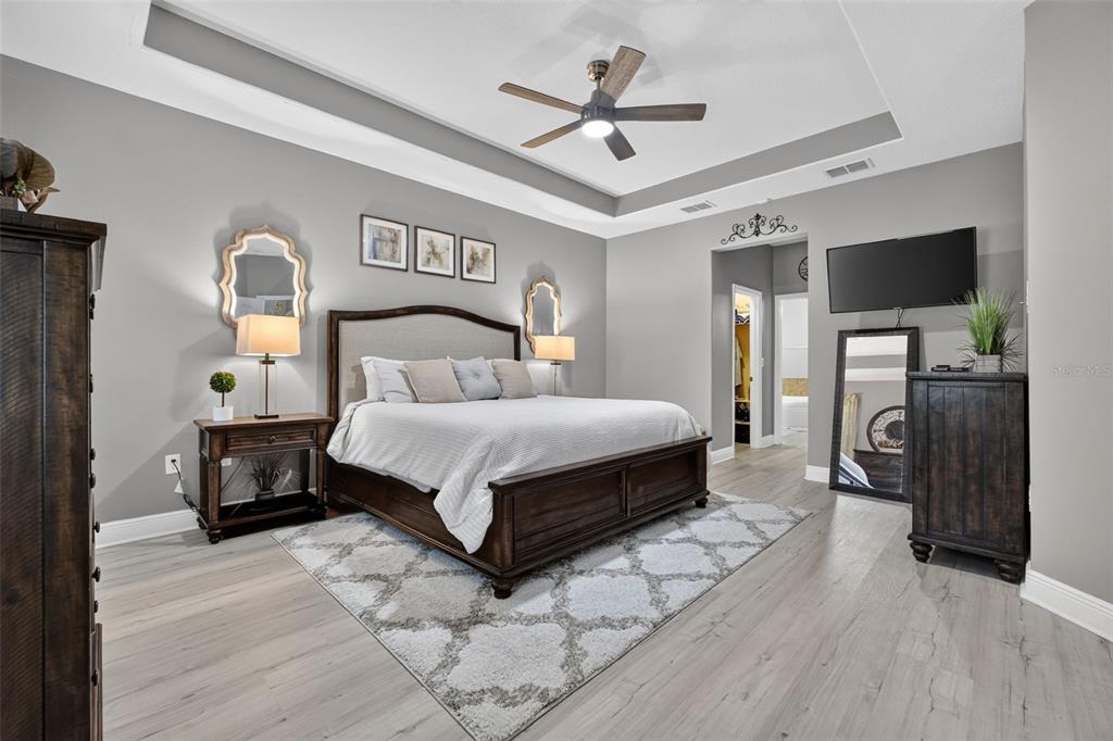 A bedroom features a wooden bed frame, gray walls, a ceiling fan, and light wood flooring — 1458 DAYSTAR LANE, DELTONA, FL
