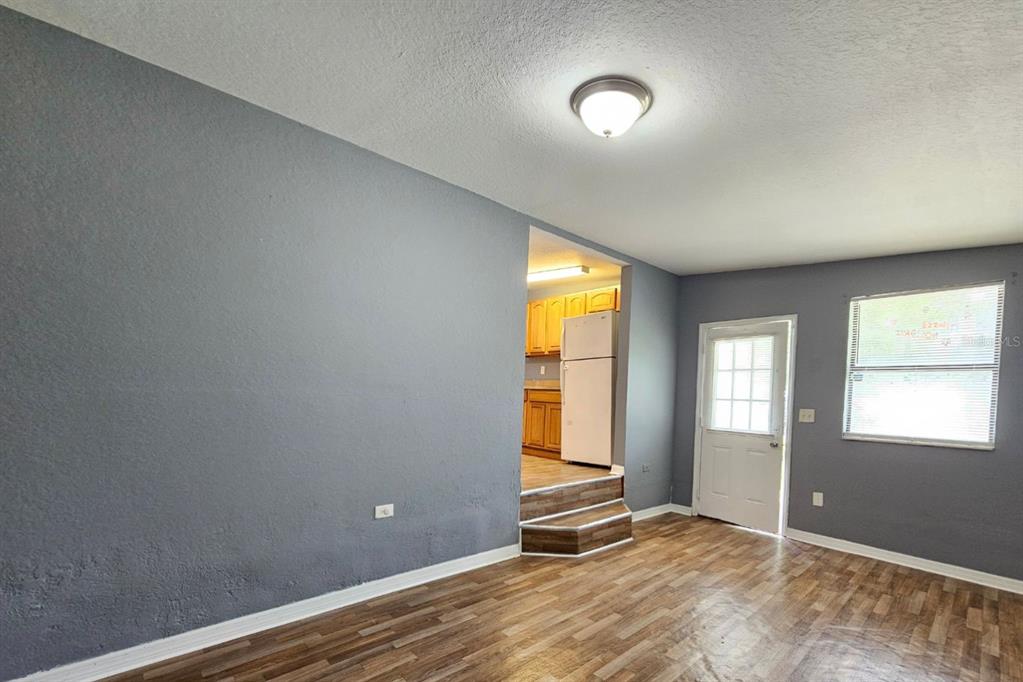 A living room with gray walls, wood-look flooring, and a step up to a kitchen — 2431 CANNON STREET, LAKELAND, FL