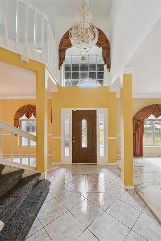A two-story foyer features a crystal chandelier, tiled floors, a wooden front door, and stairs — 6415 ABBEYDALE COURT, ORLANDO, FL