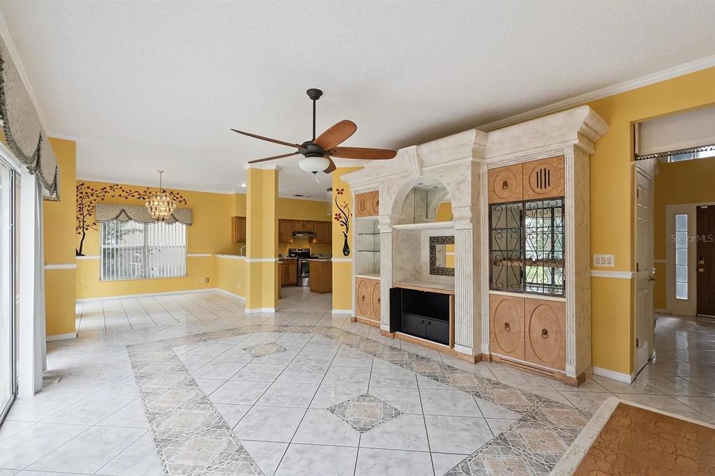 A living room with yellow walls, tile flooring, a ceiling fan, and a built-in cabinet — 6415 ABBEYDALE COURT, ORLANDO, FL