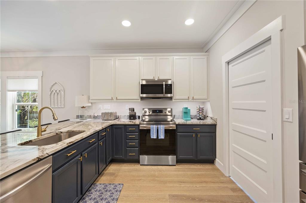 A kitchen features two-toned cabinetry, a stainless steel range, and a marble-patterned countertop — 1623 8TH AVENUE W, BRADENTON, FL