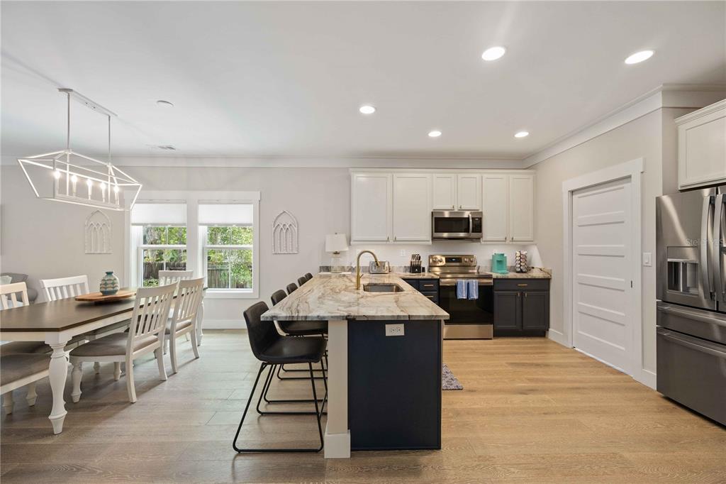 A kitchen and dining area with white upper cabinets, dark lower cabinets, and a stone island — 1623 8TH AVENUE W, BRADENTON, FL