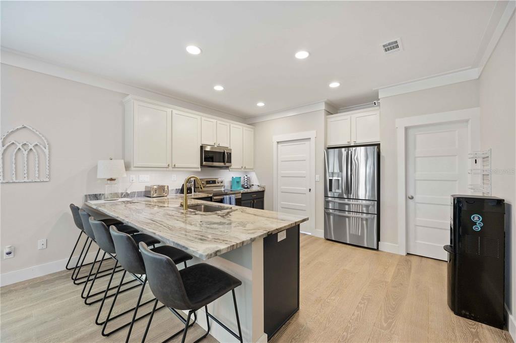 A modern kitchen features a marble-topped island with bar seating and white cabinetry — 1623 8TH AVENUE W, BRADENTON, FL
