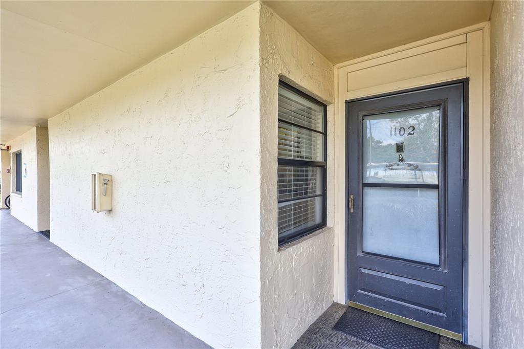 A view of an exterior apartment entryway with a grey door and a window — 12300 VONN ROAD UNIT 1102, LARGO, FL
