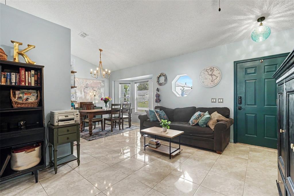 A living and dining area features tile floors, a dark sofa, and a green door — 534 DAVIDSON STREET SE, PALM BAY, FL