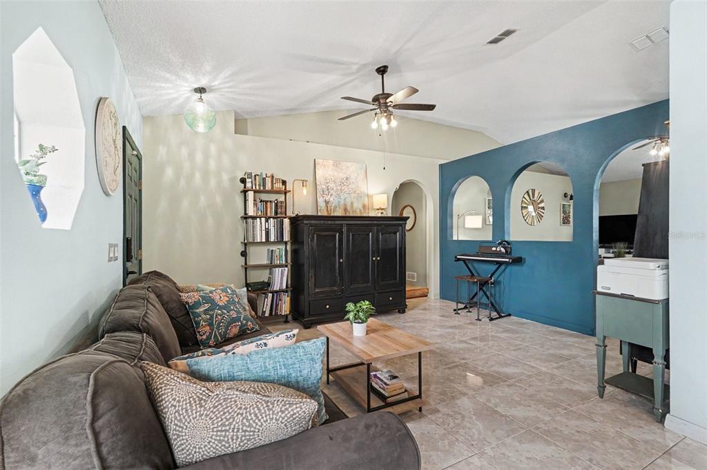 A living room features a dark sofa, a black cabinet, and blue arched wall cutouts — 534 DAVIDSON STREET SE, PALM BAY, FL