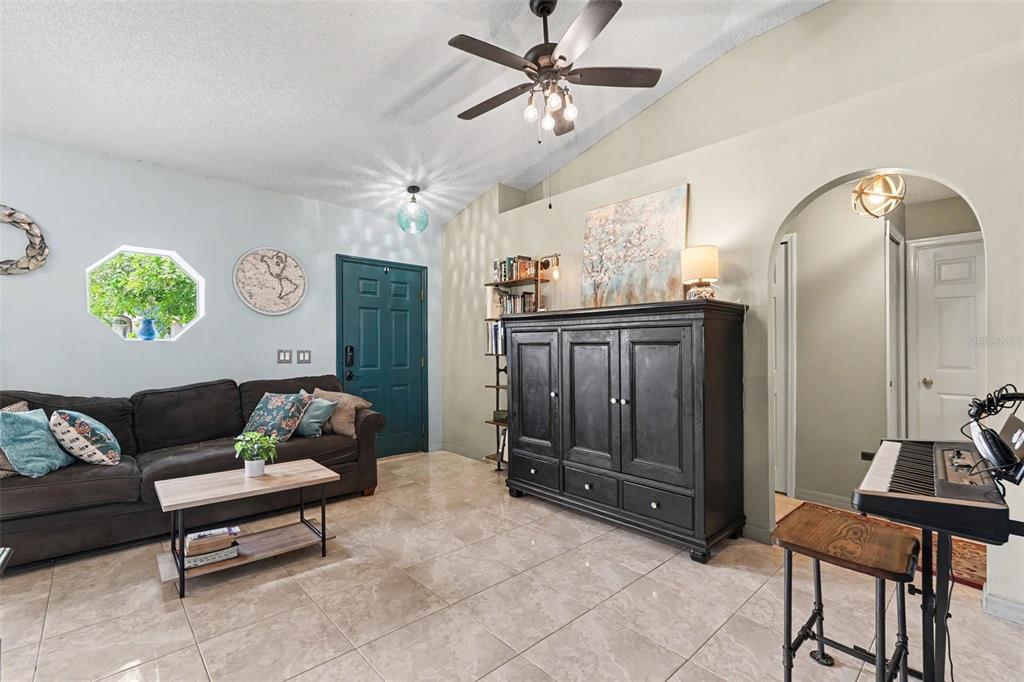 A living room with tile floors, a dark sofa, a large cabinet, and a ceiling fan — 534 DAVIDSON STREET SE, PALM BAY, FL